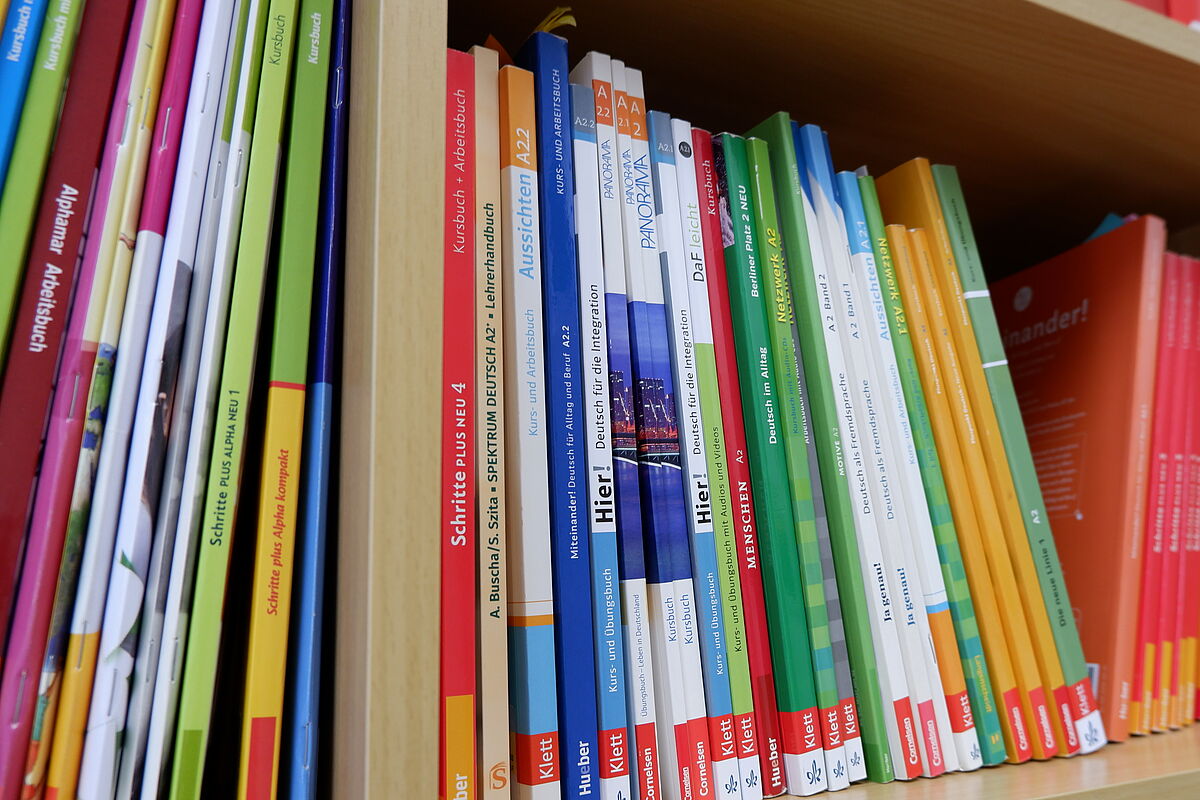 In einem Bücherregal stehen verschiedene Lehr- und Lernmaterialen aus dem Bereich DaF/DaZ.